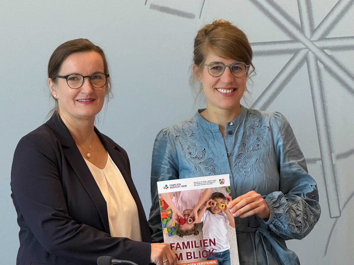 Prfo. Dr. Susanne Kuger, links im Bild, und die nordrhein-westfälische Familienministerin Verena Schäffer, rechts im Bild, halten den NRW-Familienbericht 2026 in Händen.