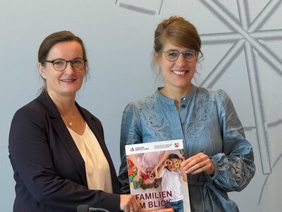 Prfo. Dr. Susanne Kuger, links im Bild, und die nordrhein-westfälische Familienministerin Verena Schäffer, rechts im Bild, halten den NRW-Familienbericht 2026 in Händen.